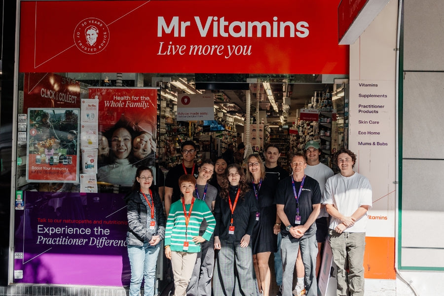 The Mr Vitamins Chatswood team standing together at the store entrance, with stocked shelves and practitioner advice signage behind them